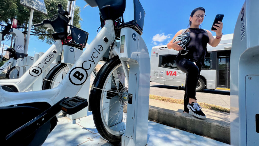 latina woman using her smart phone to use a bike share system